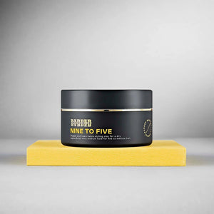 BARBER BARBER Nine To Five Medium Hold Styling Clay 100g, tarro negro sobre bloque amarillo, estudio gris