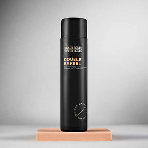 BARBER BARBER Double Barrel Shampoo 200ml, vista frontal de botella negra sobre bloque de cuero, estudio gris