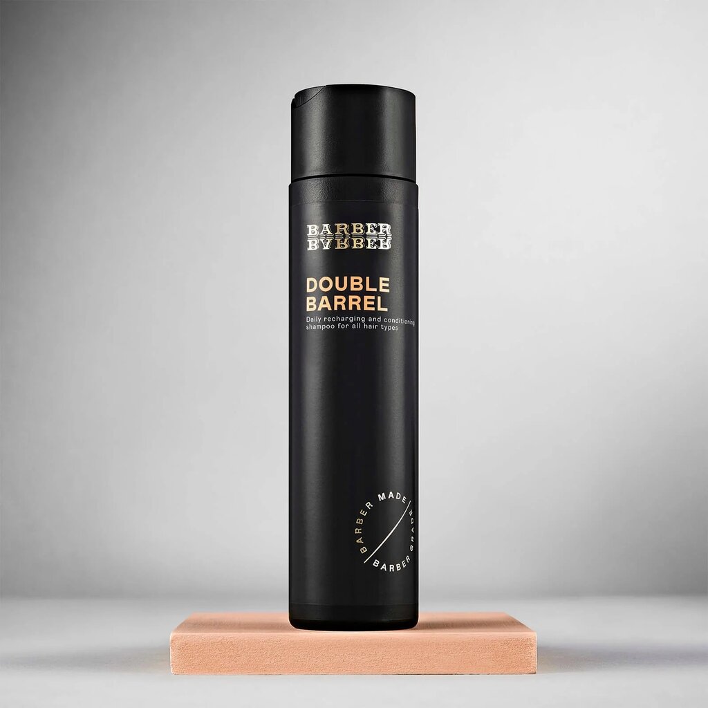 BARBER BARBER Double Barrel Shampoo 200ml, vista frontal de botella negra sobre bloque de cuero, estudio gris