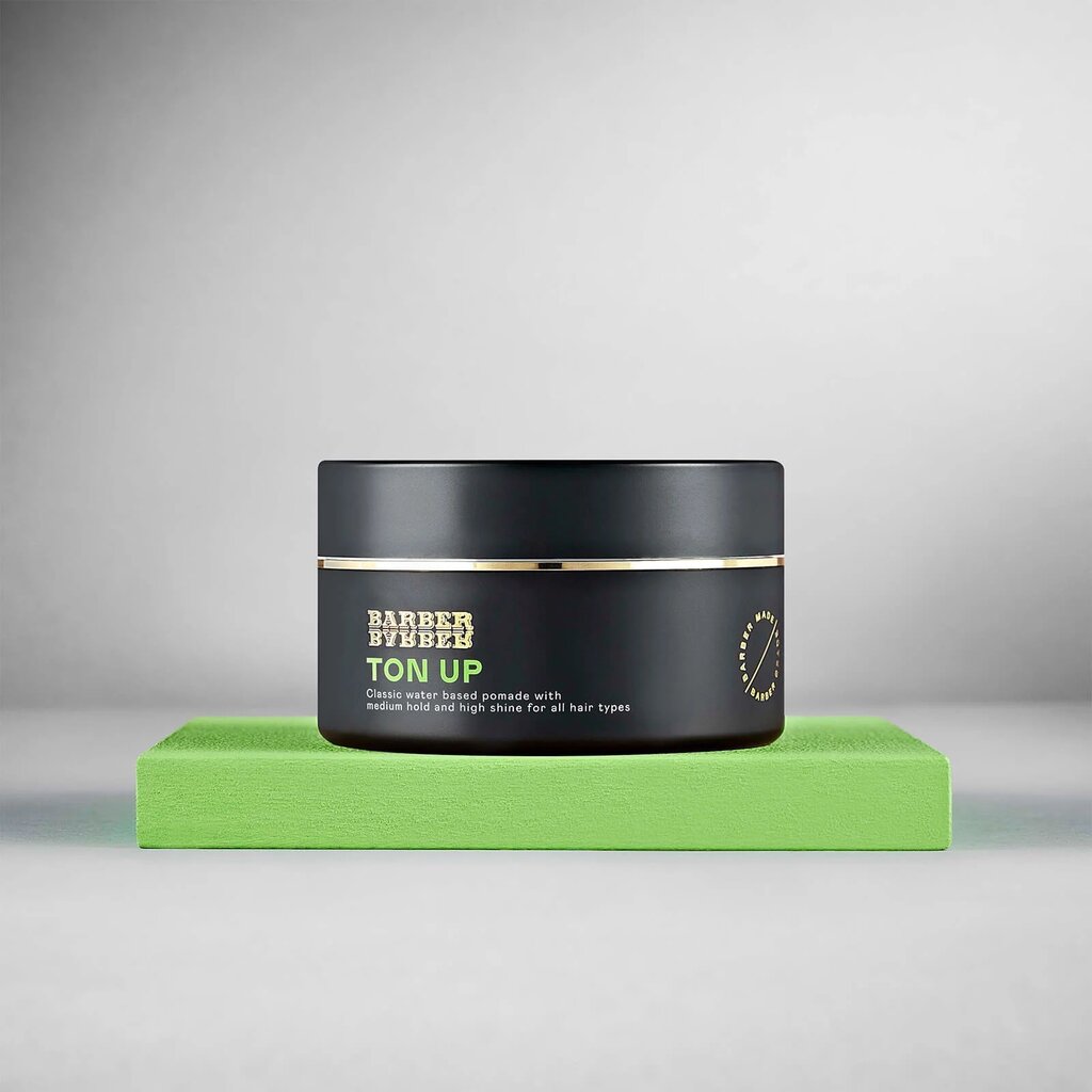 BARBER BARBER Ton Up Water-Based Pomade 100g, tarro negro sobre bloque verde, estudio gris