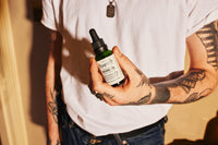 Pomp & Co. Beard Oil, man houdt het groene glazen flesje vast