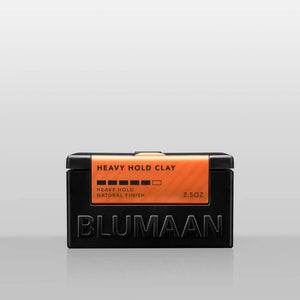 Blumaan Heavy Hold Clay, vista frontal del tarro negro con etiqueta naranja, acabado natural